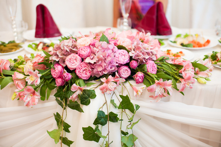 Pink bouquet of hydrangeas and peonies lies on the dinner tableの写真素材