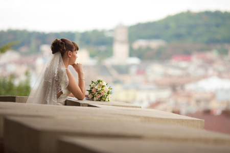 A look from afar on a thoughtful bride leaning on the balconyの写真素材