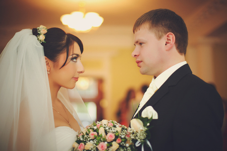 Bride and groom look at each other attentively standing in the hotel hallの写真素材