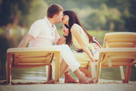 A picture in warm tones of young couple sitting on the beach bedsの写真素材