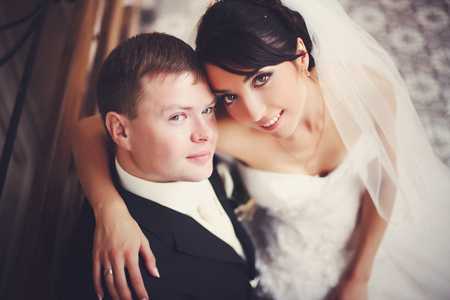 Bride with hazel eyes looks up sitting on groom's kneesの写真素材