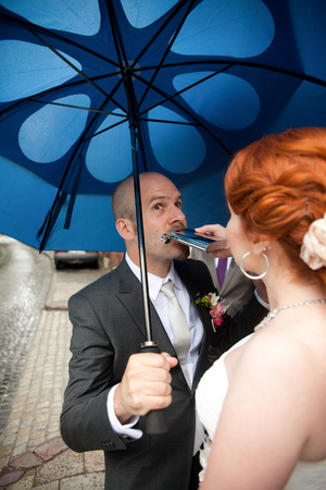 Groom drinks from the flask standing under blue umbrellaの写真素材