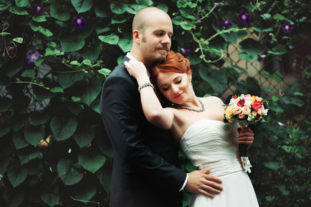 Groom clothes his eyes embracing a stunning brideの写真素材