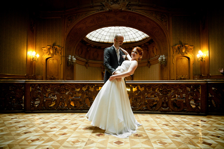 Groom holds bride in his hands standing in the middle of old wooden hallの写真素材