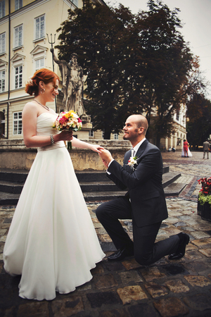 Groom stands on the knee before a brideの写真素材