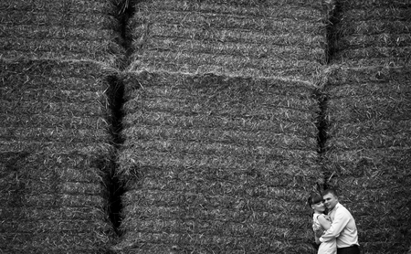 Black and white picture of stunning couple hugging behind a wall of haycocksの写真素材