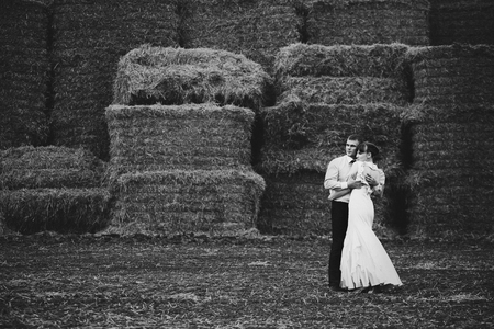 Woman in evening gown leans to a man posing behind the hayの写真素材