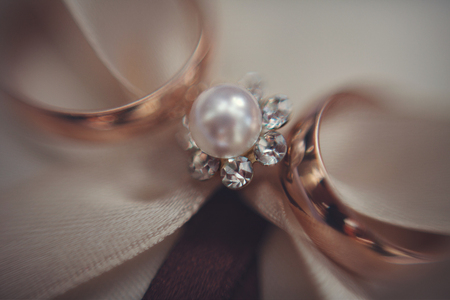 Blurred picture of wedding rings lying over the pearl broochの写真素材