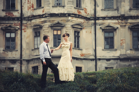 Groom helps bride to walk from the old castleの写真素材