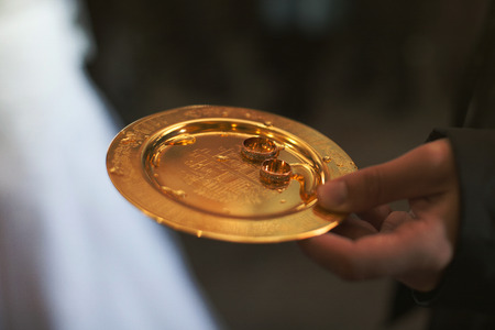 Man holds a golden plate with gorgeous wedding ringsの写真素材