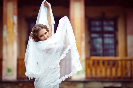 Bride looks like a bird raising a veil on her handsの写真素材