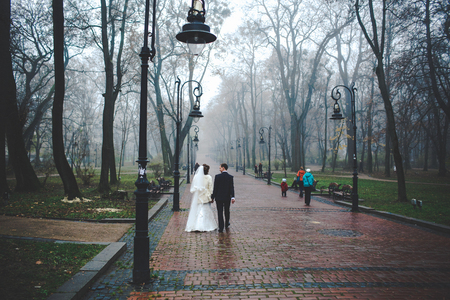 Newlyweds talk while walking under the lanterns in the foggy parkの写真素材