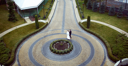 A look from above on the newlyweds walking behind round flowerpot on the backyardの写真素材