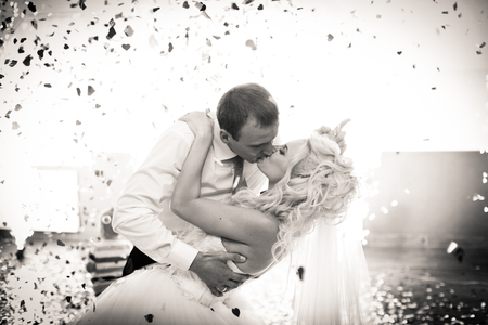 Black and white picture of a groom kissing curly bride while bending her overの写真素材