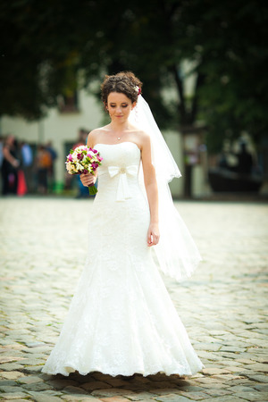 Tiny brunette bride walks careful on the pavementの写真素材