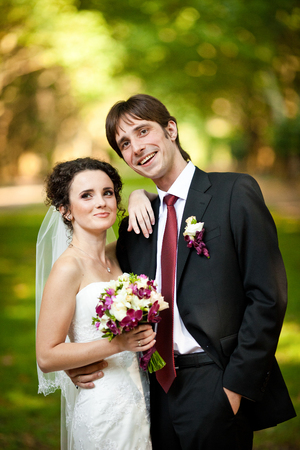 Groom smiles sincerely while bride holds her hand on his shoulderの写真素材