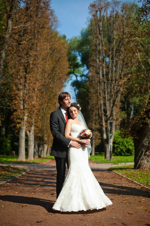 Bride daydreams leaning to groom's chest somewhere in the parkの写真素材