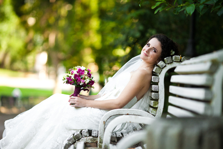 Sweet bride rests on white bench in the parkの写真素材