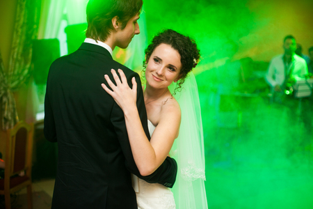Smiling bride looks from the groom's shoulder while dancingの写真素材