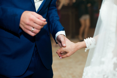 A closeup of newlyweds hands held together during a danceの写真素材