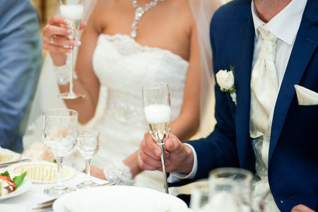 Stylish bride and groom hold in their hands steel champagne flutesの写真素材