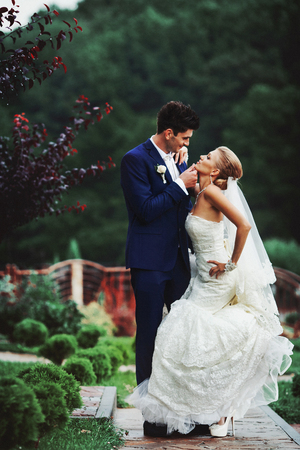 Groom holds bride's chin admiring her in the gardenの写真素材
