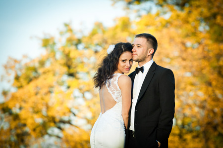 Curly brunette bride in a gown with open back leans to a groomの写真素材