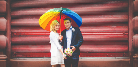 Bride and groom pose under the colored umbrellaの写真素材