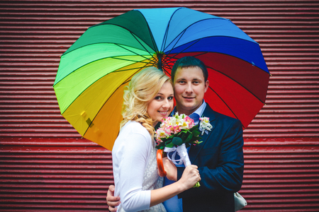 Bright picture of stylish newlyweds posing behind a red wallの写真素材
