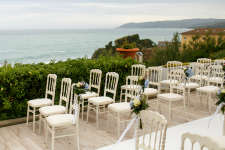 Little bouquets beautified with blue and white flowers put on the chairs' backsの写真素材