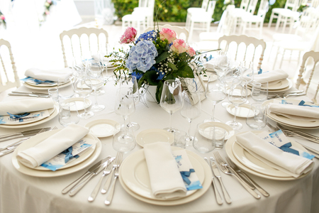 Silver cutlery and white crockery stand on the round dinner tableの写真素材