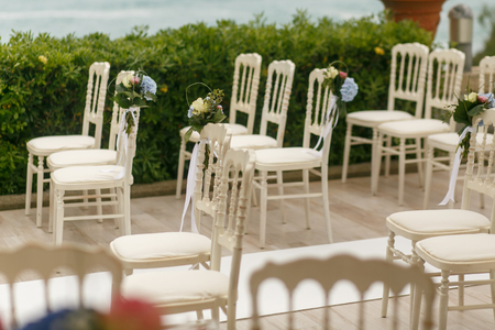 White chairs stand on the different sides of the path to wedding altarの写真素材