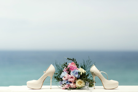 White shoes stand on different side of wedding bouquetの写真素材