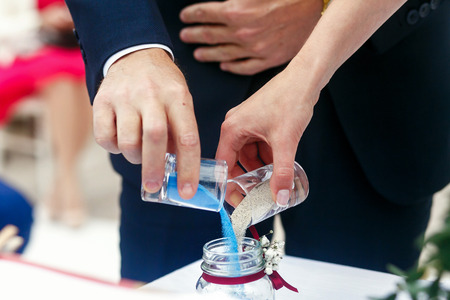 Bride and groom strew coored sand in the bottleの写真素材
