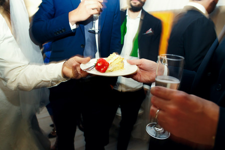 Waiter gives to a man a plate with strawberrie and piece of wedding cakeの写真素材