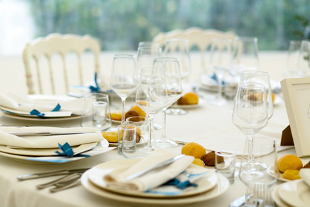 Little cookies on white plates stand around the crockery on dinner tableの写真素材