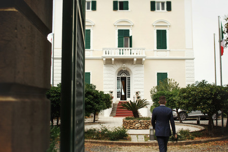 Man in black suit walks to the beautiful white houseの写真素材