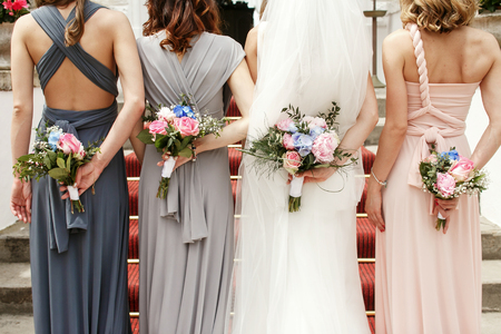 Look from behind on bride and bridesmaids hiding the wedding bouquetsの写真素材