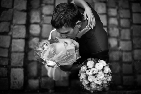 A look from above on a man kissing a bride in a little hat with short veilの写真素材