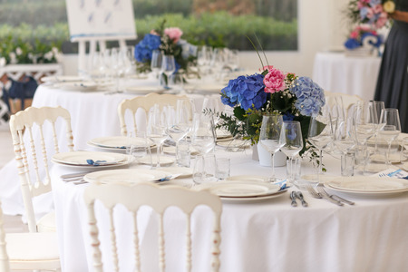 Original white chairs stand around rich dinner tableの写真素材