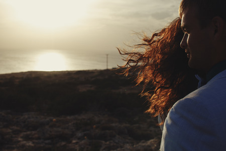 Evening sun shines though the woman's curls covering man's faceの写真素材