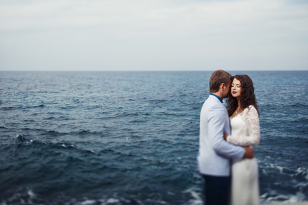 Couple stands calm by the sea enjoying the moment of peaceの写真素材