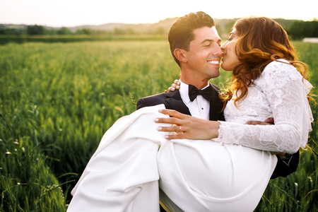 Italian groom carries elegant bride through the fieldの写真素材