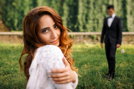 Curly woman holds her shoulders tender while posing in the parkの写真素材