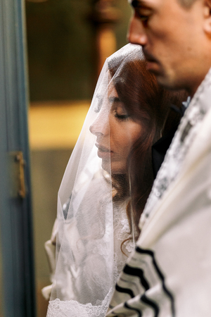Jewish wedding. Bride leans to groom's shoulder during the ceremonyの写真素材