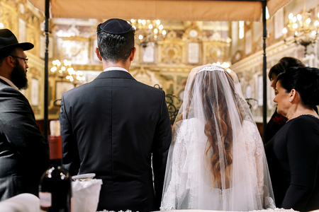 Look from behind at Jewish newlyweds standing in the synagogueの写真素材