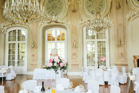 Magnificent crystal chandelier hang over the white dinner tablesのeditorial素材