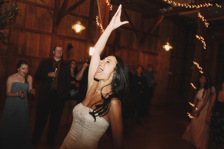 Laughing bride screams while throwing her wedding bouquetの写真素材