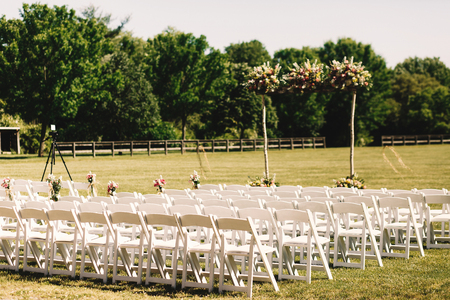 Many white chairs stand in rows before a wedding altar on the fieldの写真素材