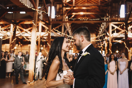 Happy newlyweds admire each other while dancing in the wooden hallのeditorial素材